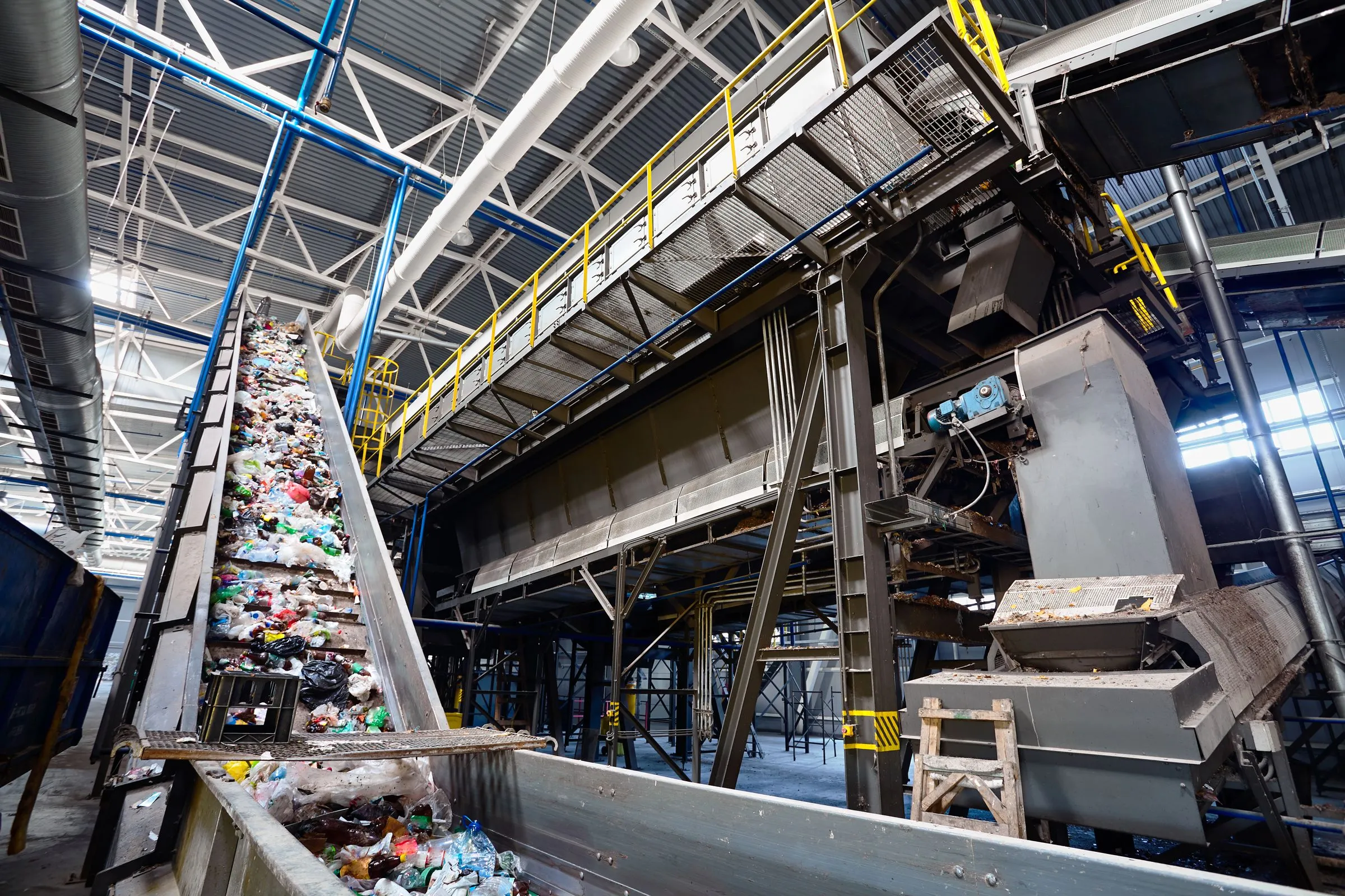 Steigendes Förderband mit Sortiergut in einer Industriehalle mit Stahlbühnen